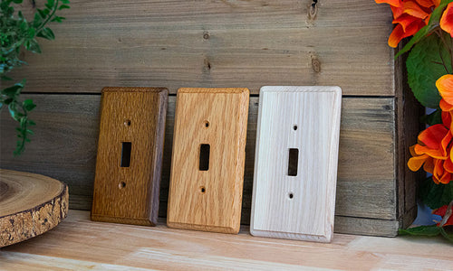 Three versions of the Contemporary wood wallplate collection lined up in front of a wood wall