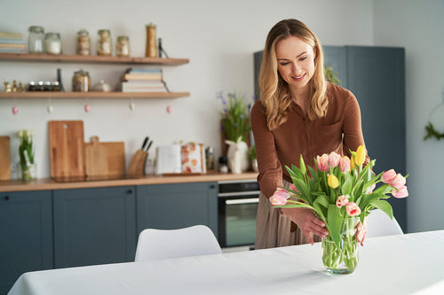 A woman decorating her kitchen with flowers during the Springtime