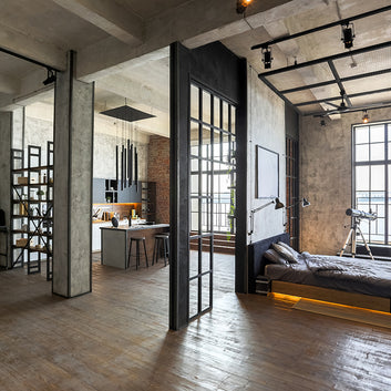 Professionally designed room with an Industrial decor style, brick walls, large windows, brick and cement walls, metal shelving, and an open floor concept