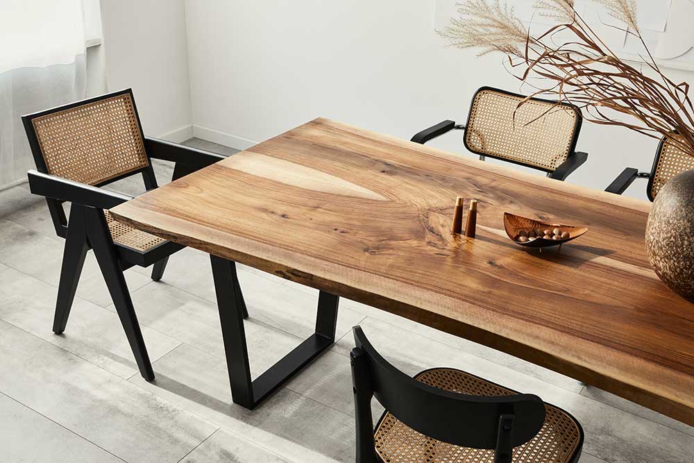 A handcrafted artisanal wood dining room table surrounded by wood and rattan chairs