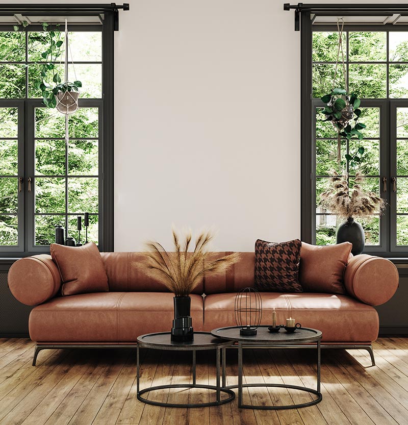 An Industrial decor style living room with wood floors, white walls, black window frames, black metal coffee tables, and an orange modern style leather couch