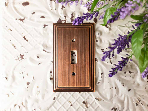 A photo of the Steps antique copper decorative metal wallplate on a beige table and lavender flowers