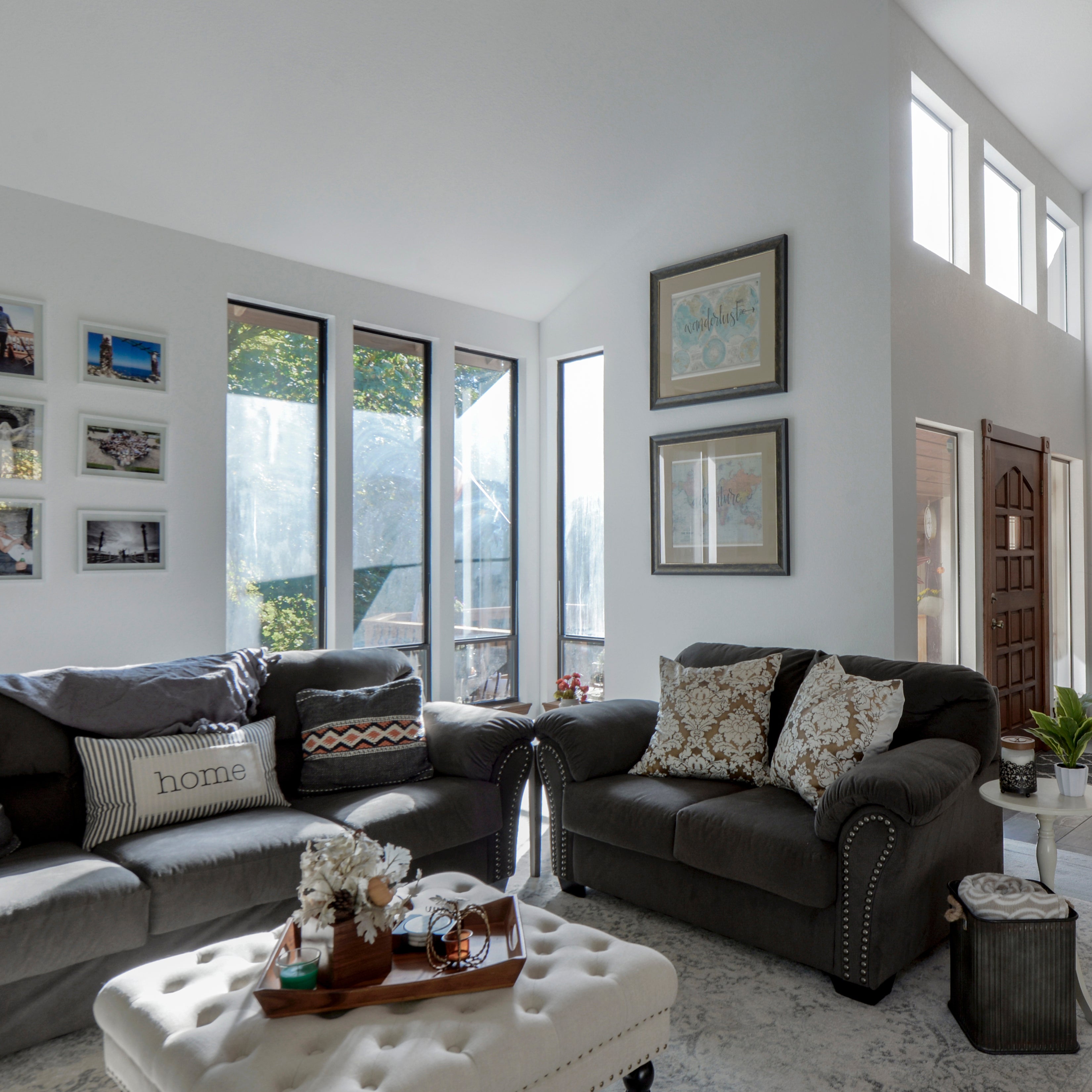 An interior photo of a professionally designed Transitional decor style living room with dark gray couches, tall windows, and other Transitional style decorations