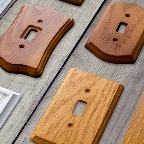 A photo of the multiple wood finished decorative wallplates on an unfinished wood table