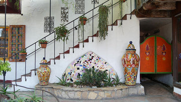 Professionally designed courtyard and stairway with colorful tiles, green plants in terracotta pots, and white stucco walls in a Spanish Colonial decor style
