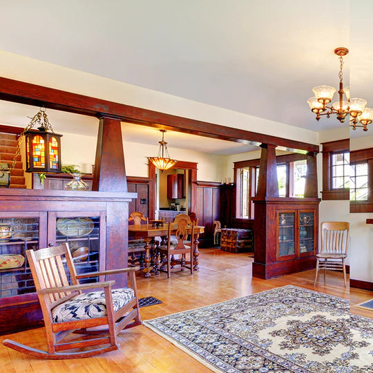 An interior photo of a professionally designed Arts and Crafts decor style living room and dining room, with stained wood architecture, wood rocking chairs, and a decorative rug on a hard wood floor