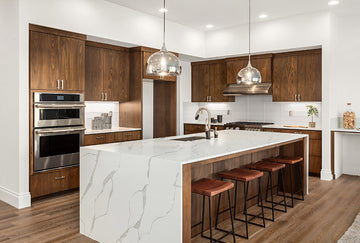 An interior photo of a professionally designed Contemporary decor style kitchen with stained wood cabinets, white marble countertops, and nickel hardware