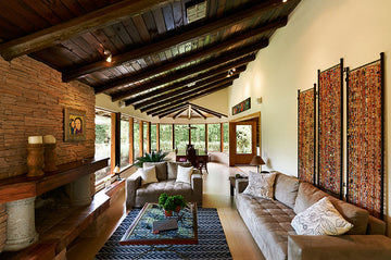 Professionally designed living room with a stained wood ceiling, a brick fireplace, and a colorful rug in a Spanish Colonial decor style