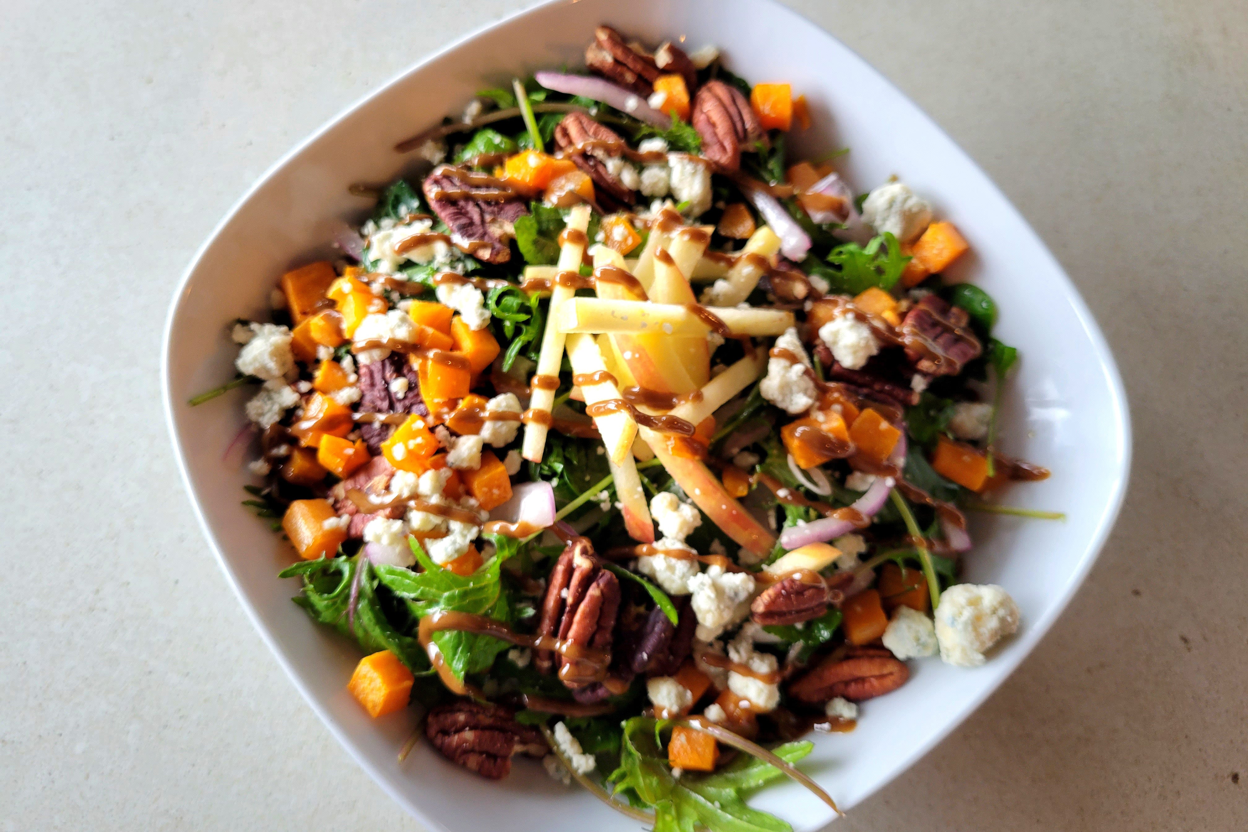 sweet potato kale salad topped with toasted pecans, sliced apples, and balsamic vinaigrette