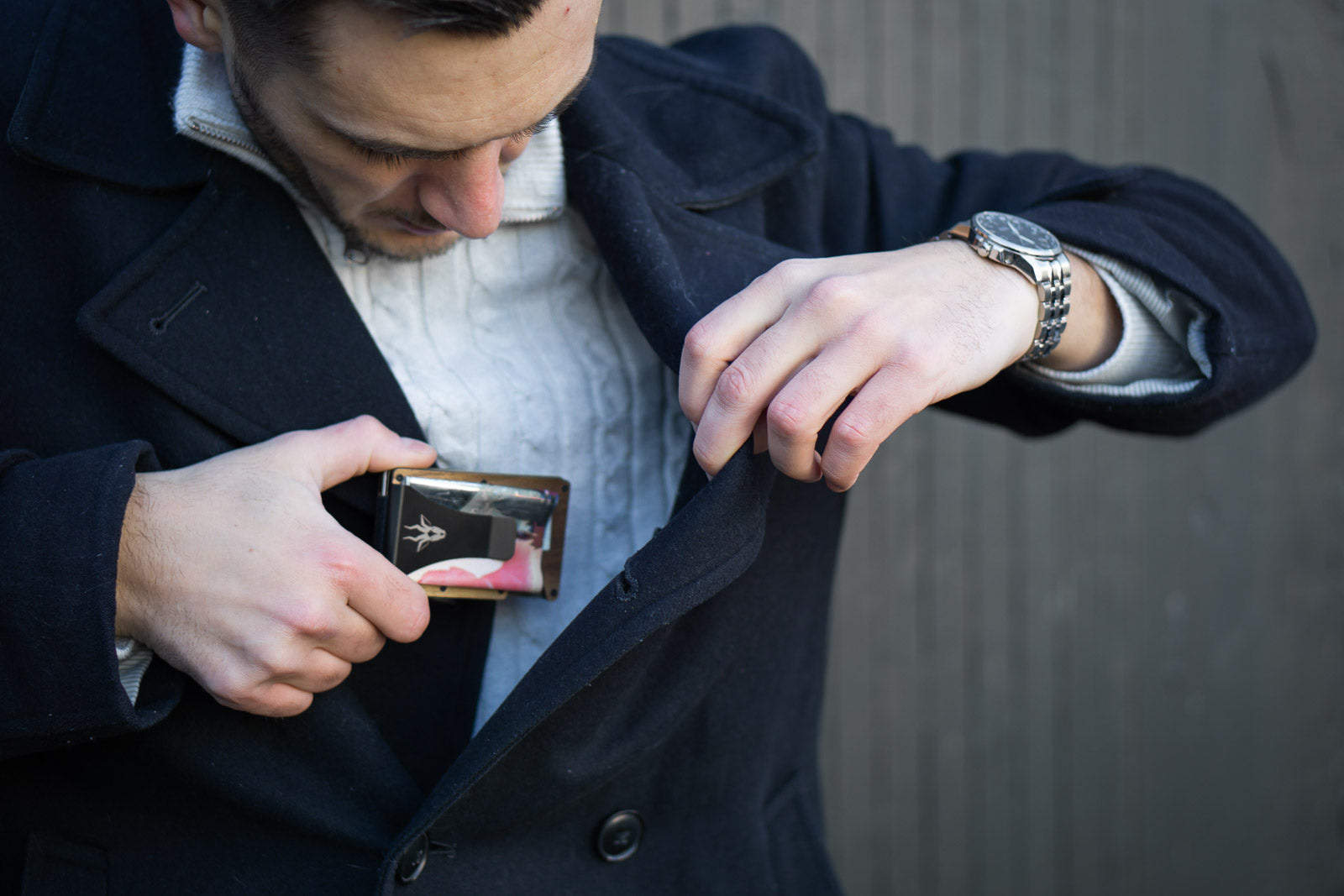 man putting minimal wallet in coat pocket mens fashion trend