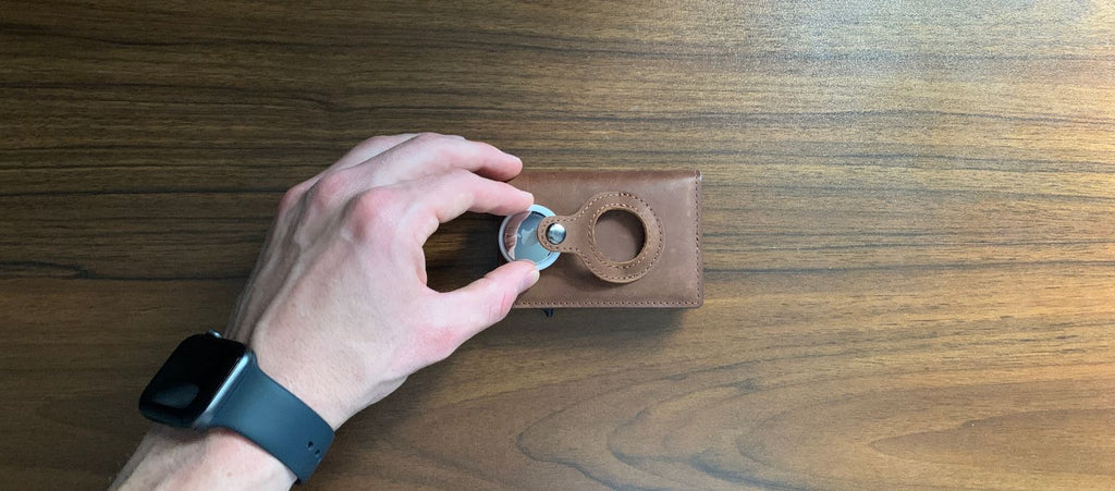 apple airtag being put into leather airtag wallet with built in design