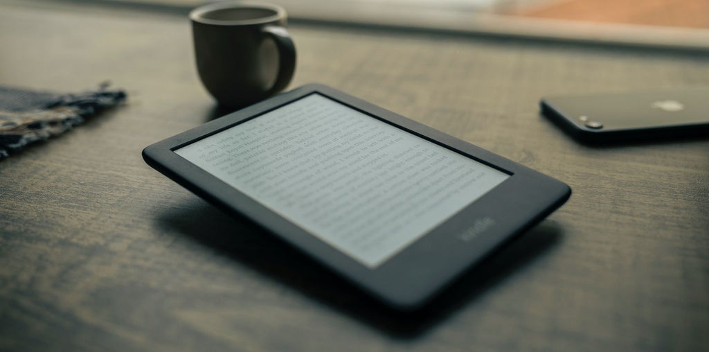 kindle on desk with phone and coffee for travel