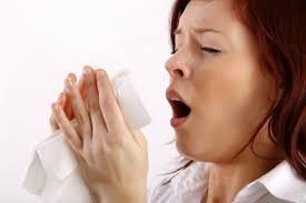 woman sneezing into a tissue