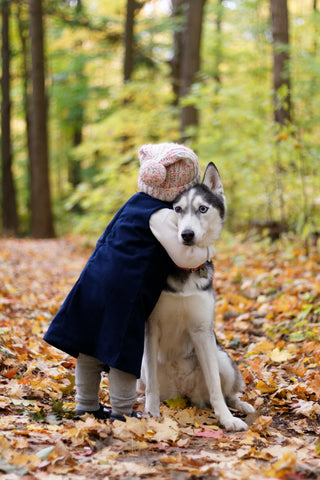 A young girl hugging her dog in the woods