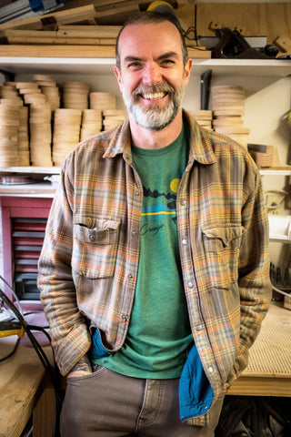 Gordon smiling in a flannel in the wood shop.