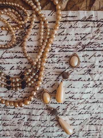 pearl necklaces, bracelets, and earrings on top of a handwritten note