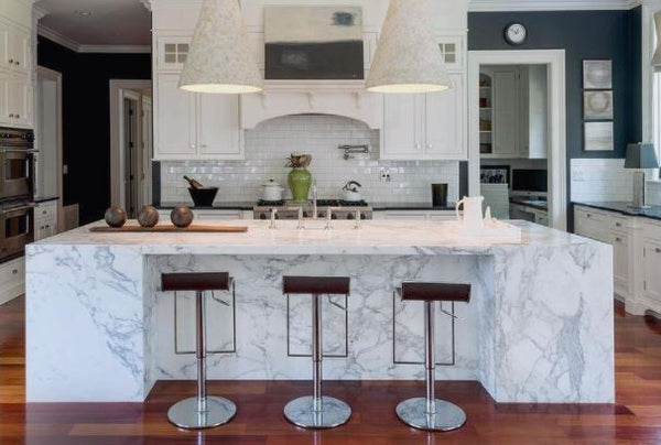 Modern kitchen with white marble island table, huge farmhouse pendant lights, white shaker type cabinet, white subway tiles and wood planks flooring