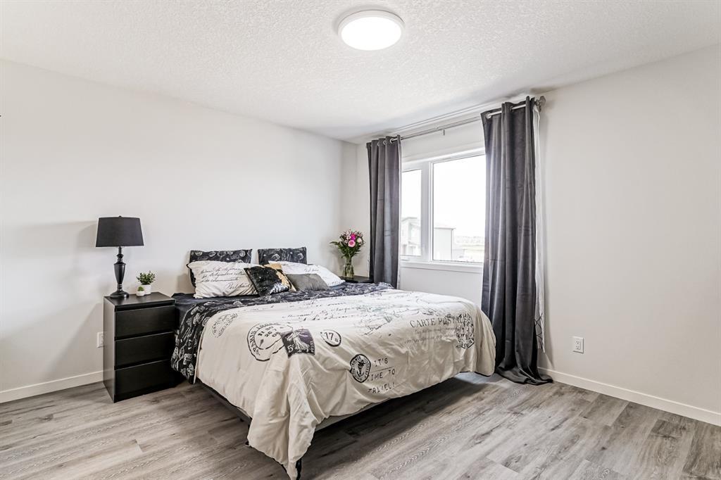 Calgary home listing showing modern and contemporary master bedroom with luxury vinyl planks white walls high ceiling and farmhouse bed