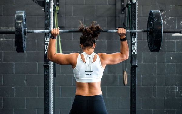 Woman lifting weight in a home gym or fitness center with grey bricks wall background