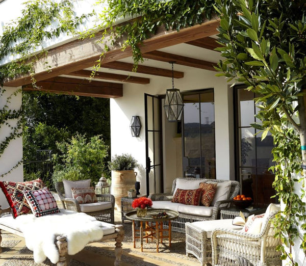 Outdoor summer patio with rattan outdoor furniture, plants, French doors and windows, accent decors and outdoor throws and pillows