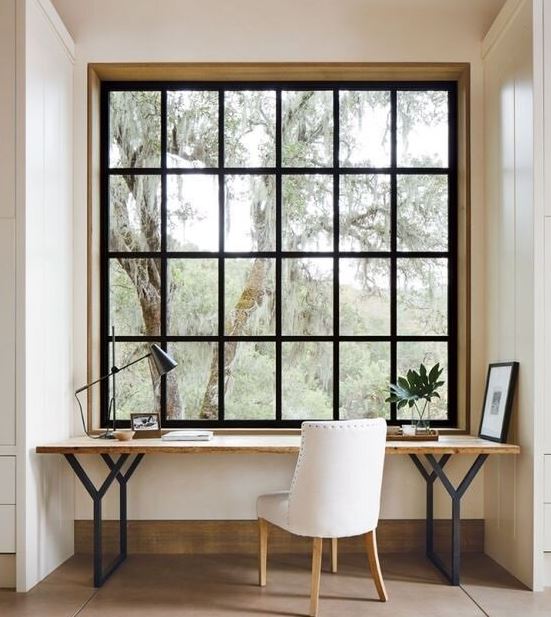 French window with wooden office desk and white office chair with potted plants and tile flooring