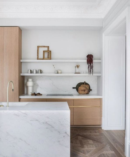 Modern kitchen with white marble island countertop, shelves, oak laminate cabinets and wood plank floor