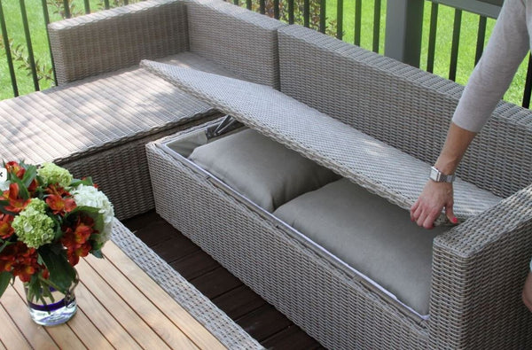 Wicker sofa with hidden storage, woman opening the storage, flower vase, patio on green grass background 