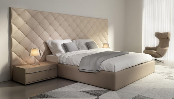 Bedroom with neutral colors white wall cream tufted padded headboard leather bed frame printed are rug wood side table and leather lounge chair