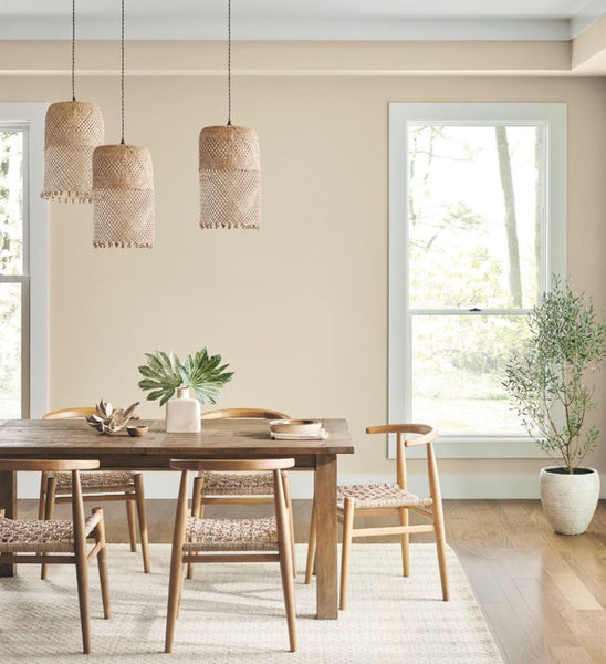 Dining area with neutral interior design palette  rattan pendant lights wood dining table and chairs rattan chairs wood plank floor cream painted walls