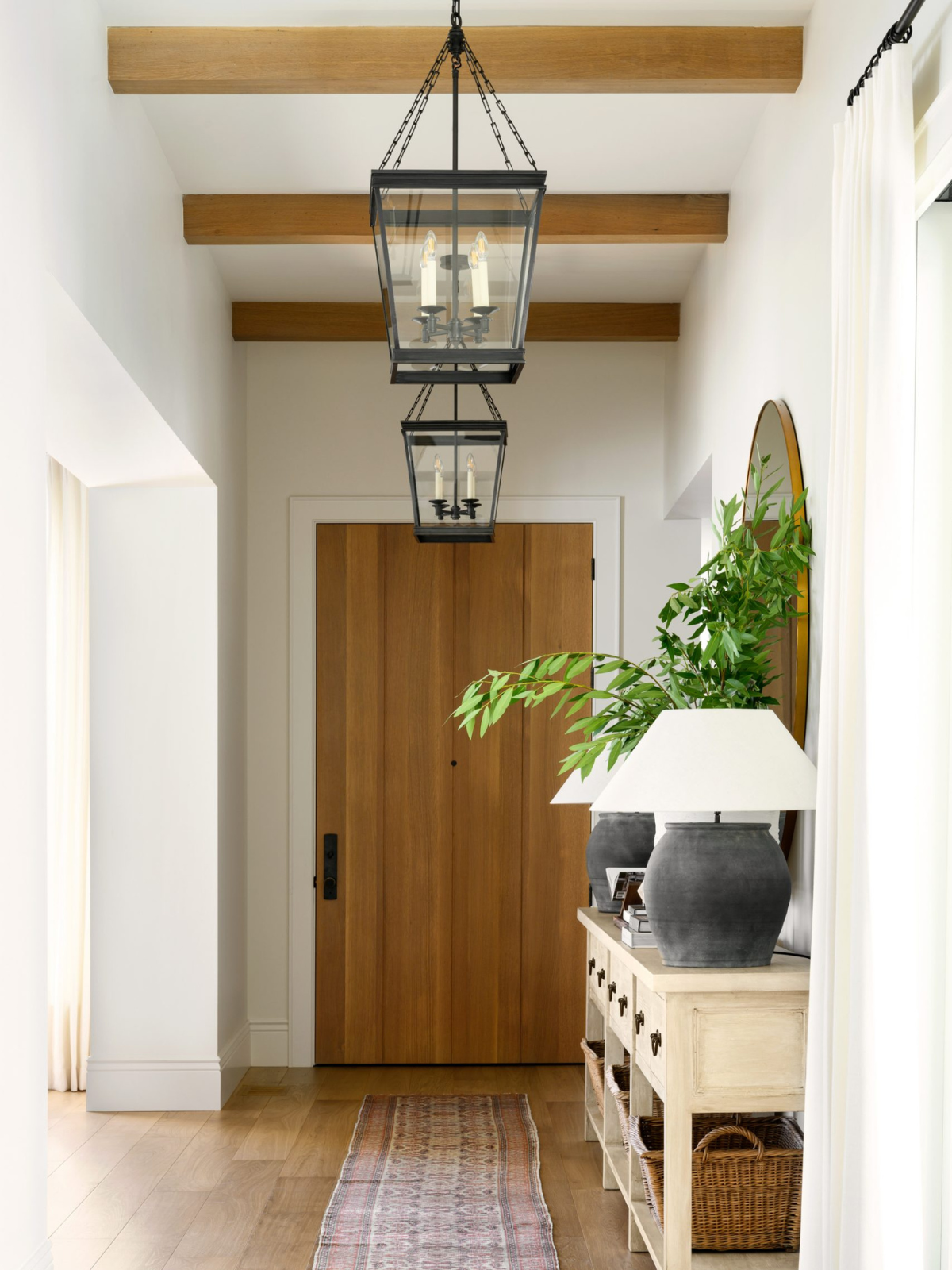 foyer with wooden floor, wood accent ceiling beams and entryway chandeliers