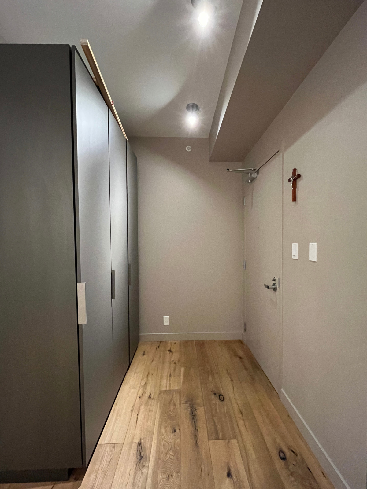 existing foyer space with grey cabinets, white ceiling, painted walls and engineered wooden floors