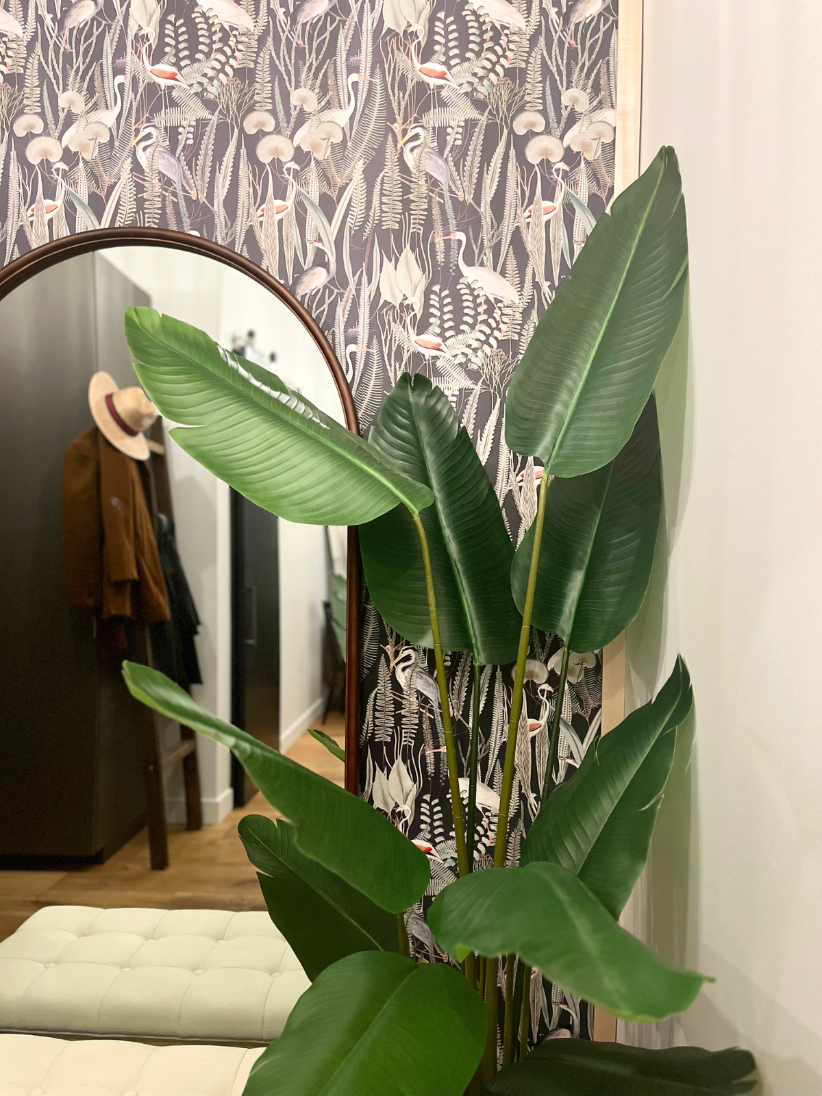 arch mirror with wooden frame, tropical inspired wallpaper and faux banana plant