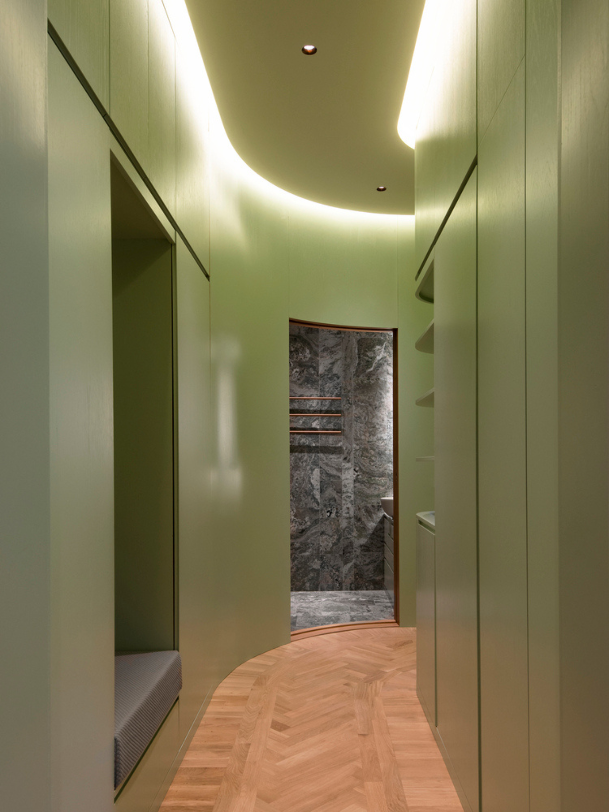 hallway with green walls and ceiling, coved lighting, niche bench, wooden floor