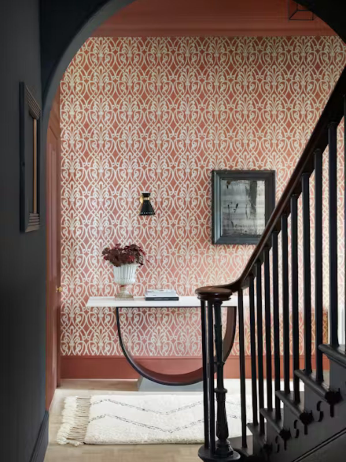 hallway view from staircase with patterned wallcovering and dark blue painted walls