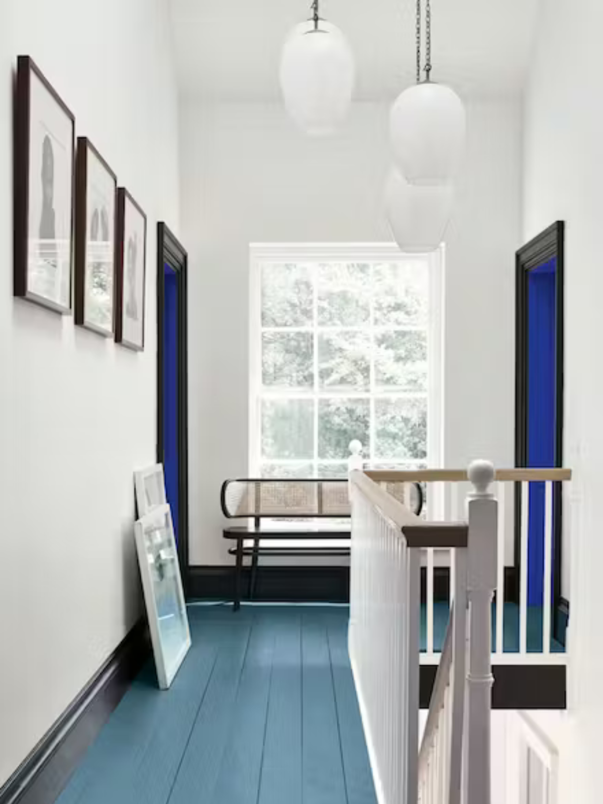 hallway with blue wooden floor, white walls and wall gallery