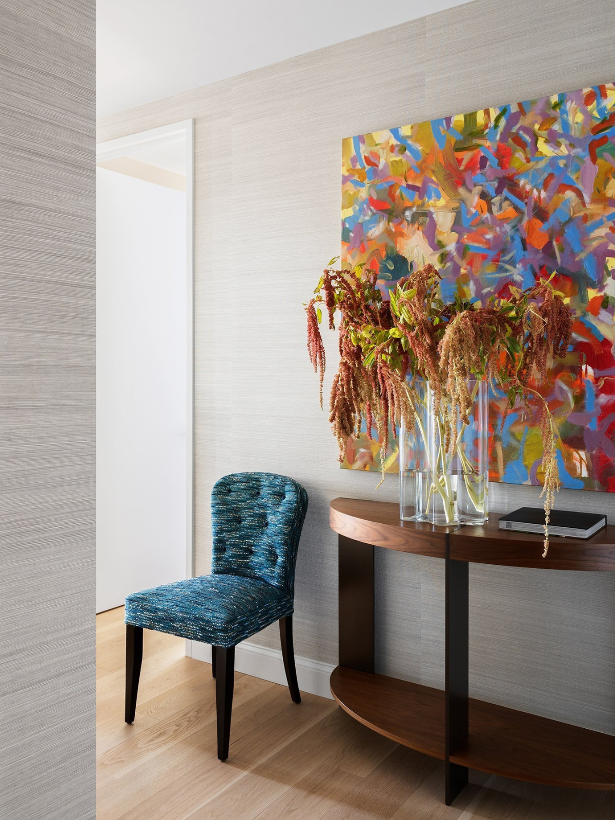 hallway with feature artwork on wall, wallcovering, lvp flooring and accent upholstered chair and console table