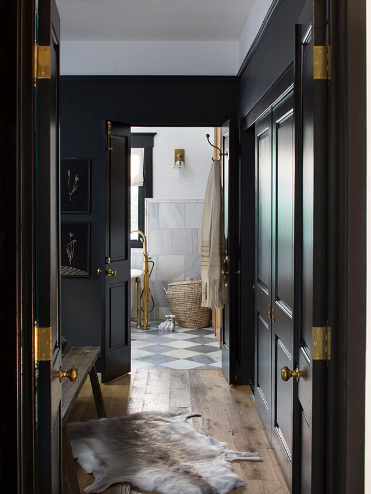 hallway with black painted walls and doors, wooden floor and accent gold hardware
