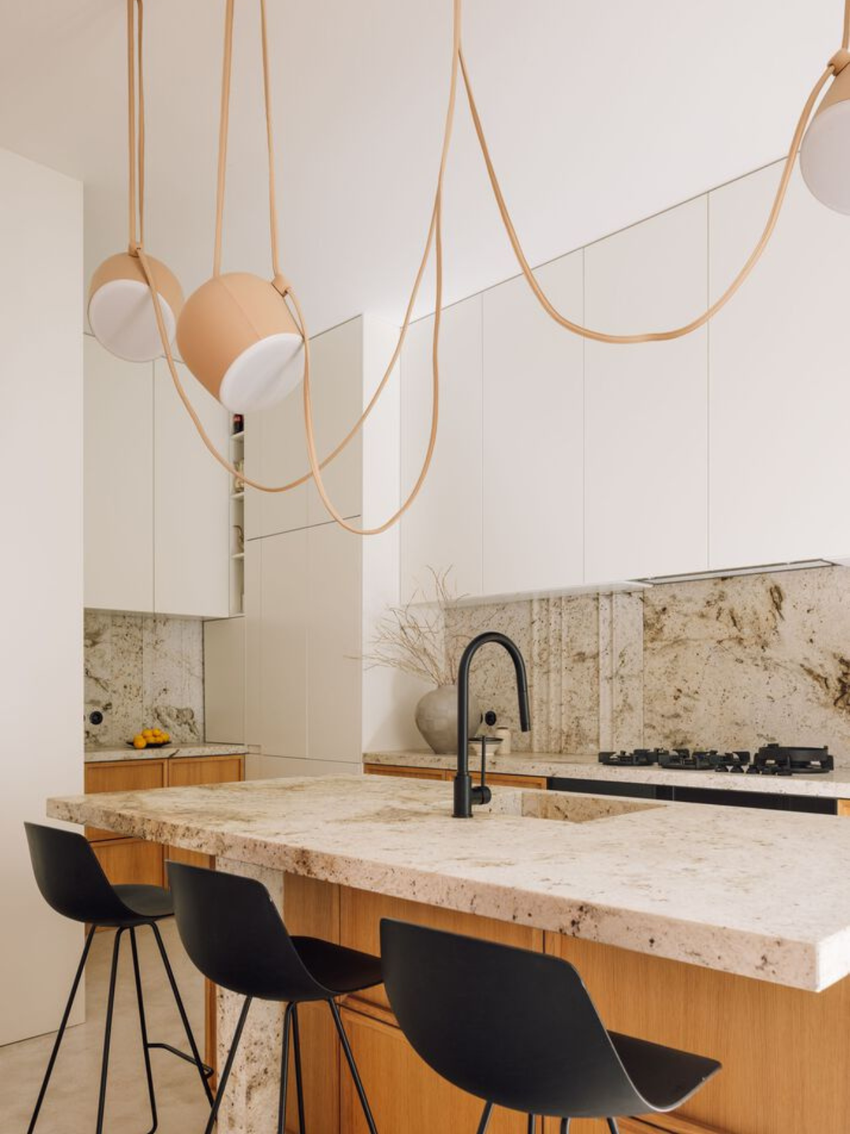 kitchen showing white cabinets, black bar stool, island counter and hanging decorative pendant lights