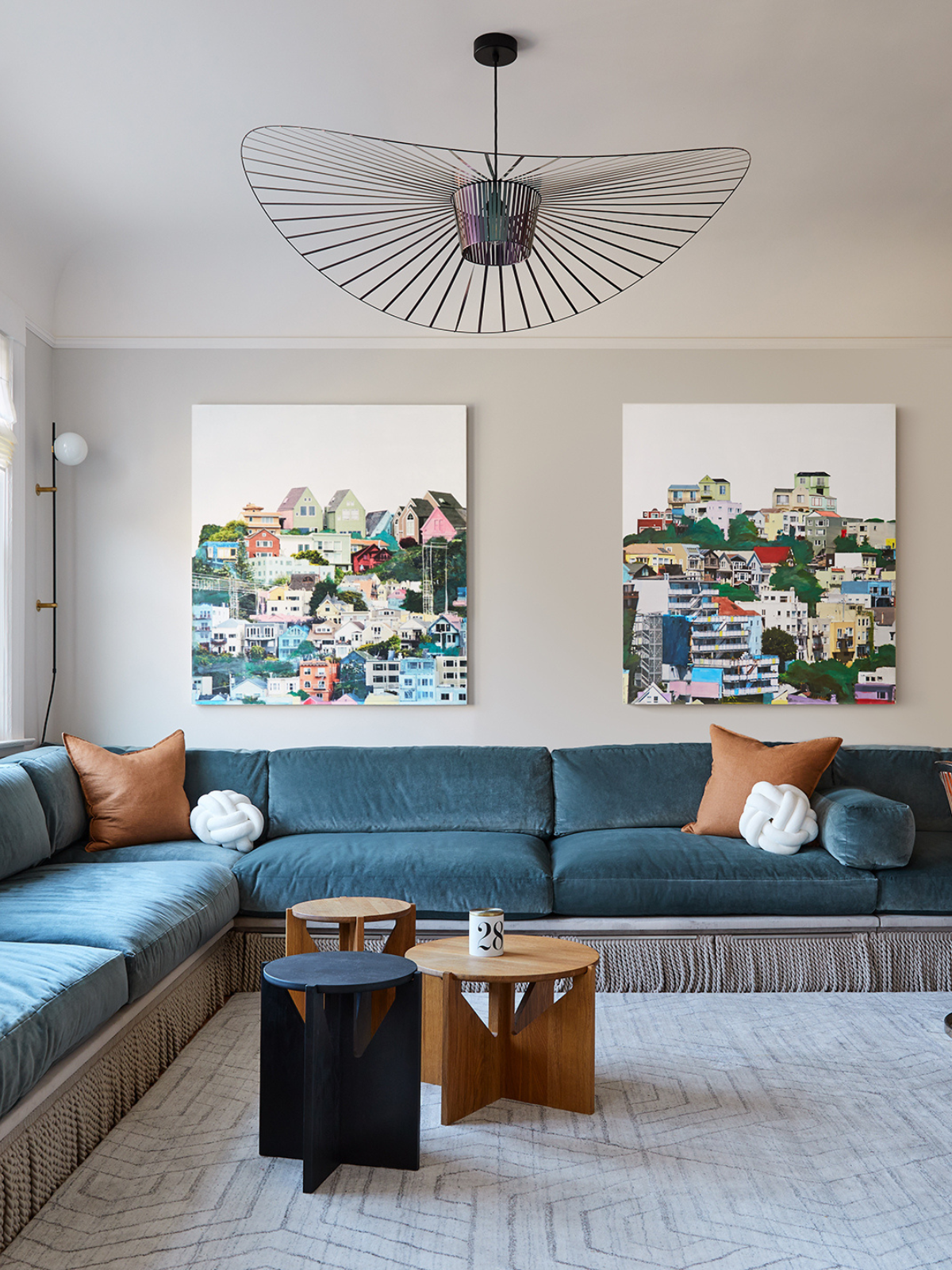 living room showing blue an L-shape sofa, rug, wall accent arts and modern pendant light