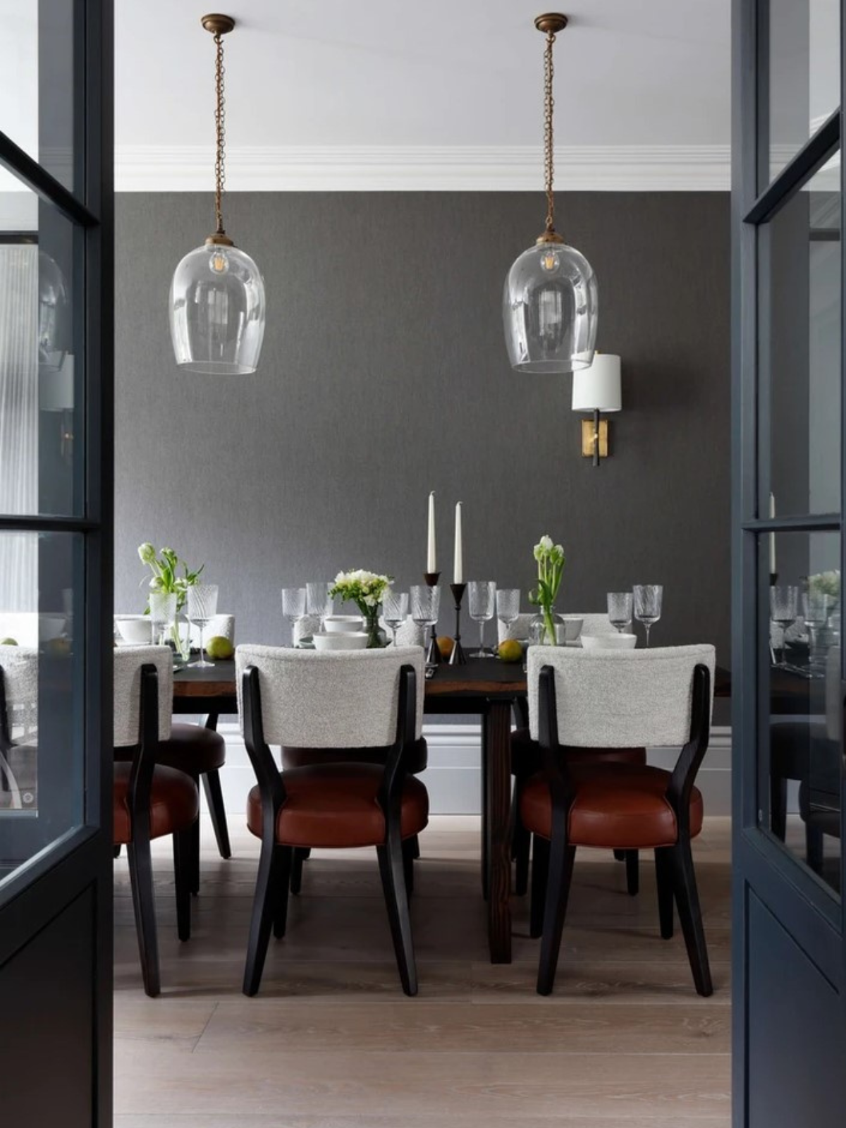 a door that opens to dining area showing grey wall accent, glass pendant lights, upholstered dining chairs and wooden floor