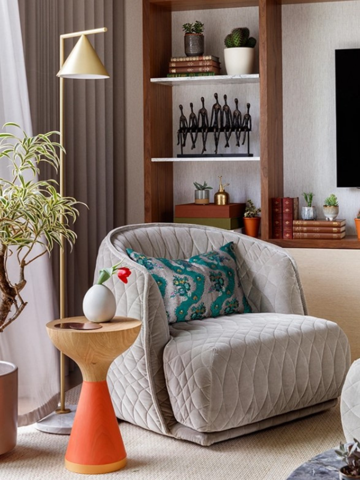 seating lounge or reading corner with grey upholstered lounge chair, golden floor lamp, wall shelves and an orange and gold side table