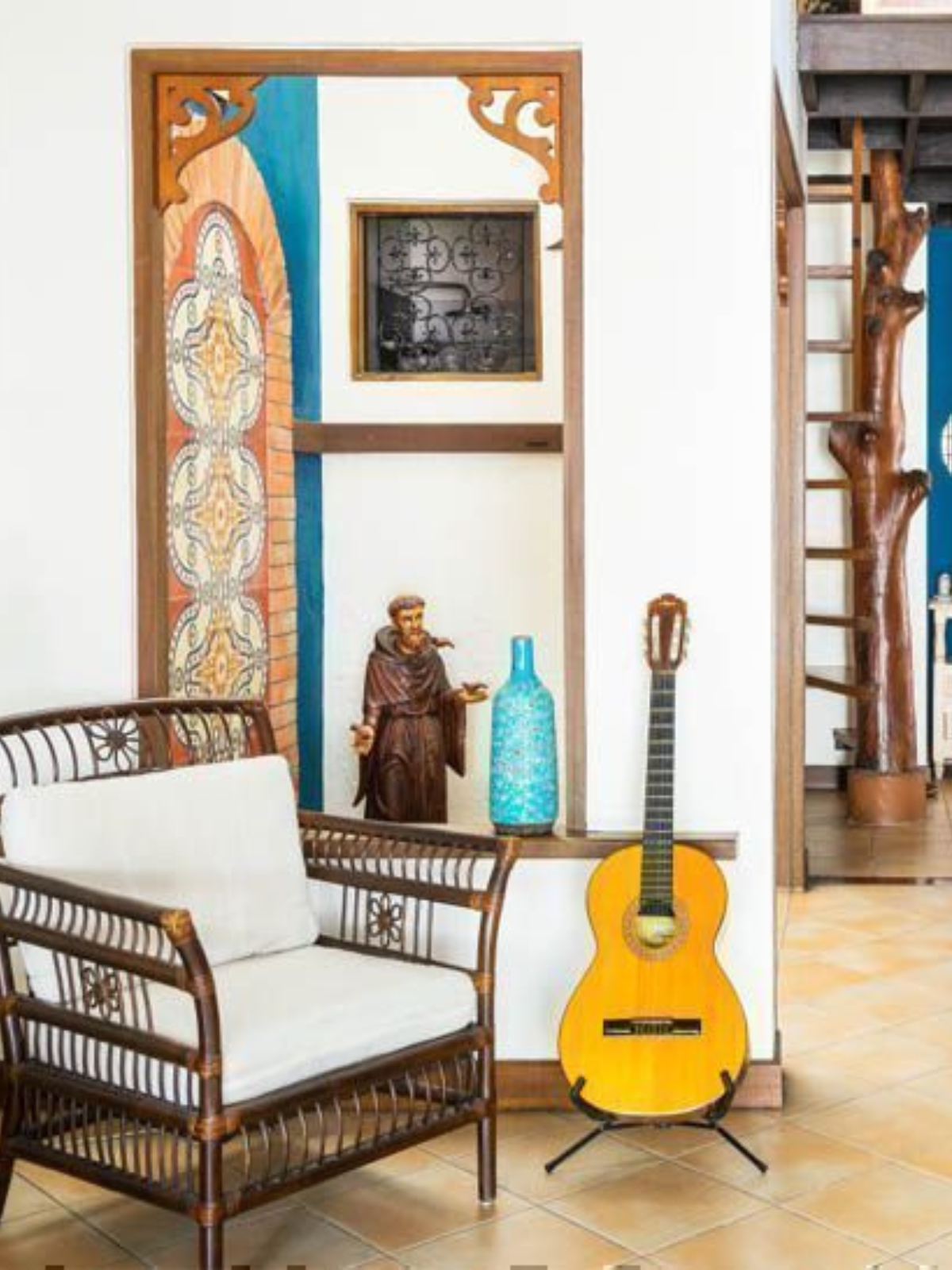 a reading corner with antique sculpture, a standing guitar, tiled flooring and wood and fabric lounge chair