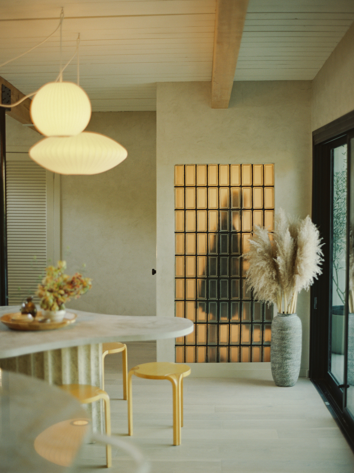 mid century modern living room showing organic shape dining table, concrete walls, accent mirrors and pendant light