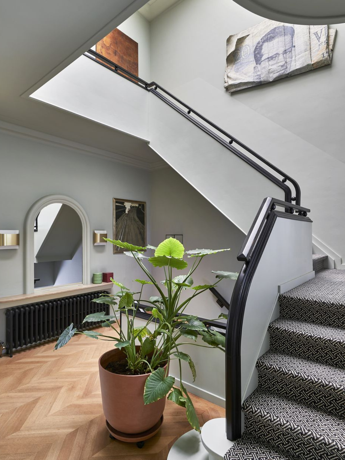 a staircase showing an accent mirror, indoor plant, wooden floor, back handrail and white walls