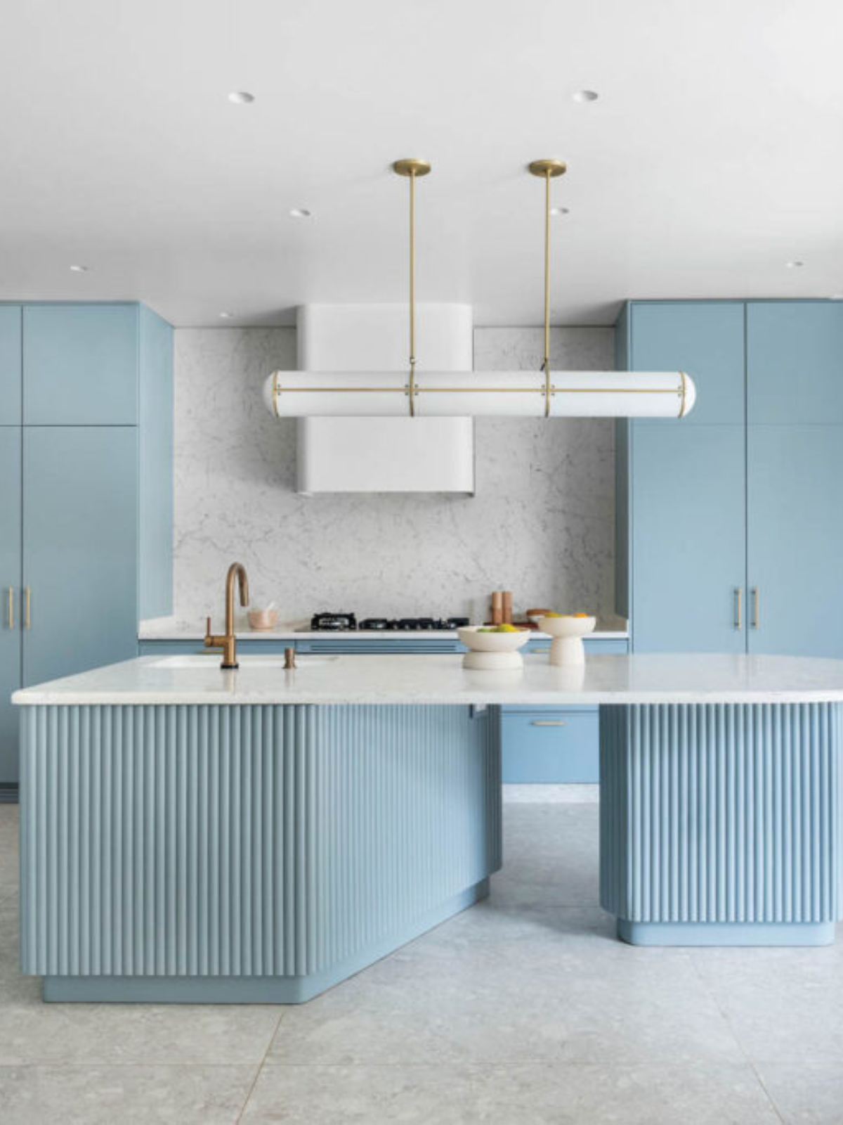 kitchen showing an island counter and millwork in powder blue finish, pendant light and gold finish plumbing fixtures