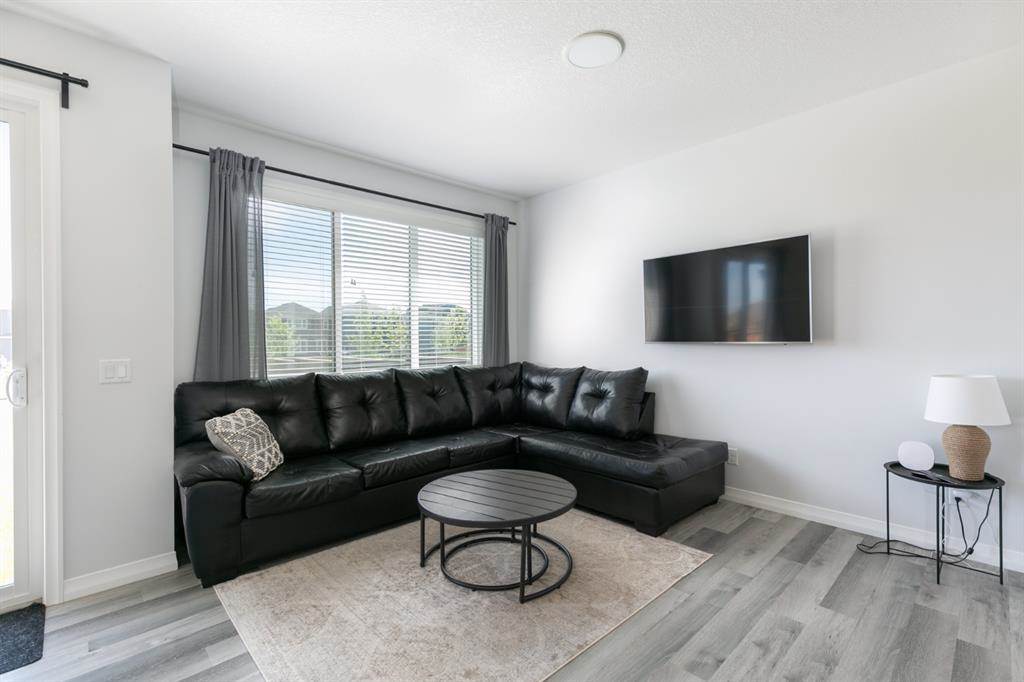 Calgary home listing interior living area with luxury vinyl planks high white ceiling pot lights black couch and white walls