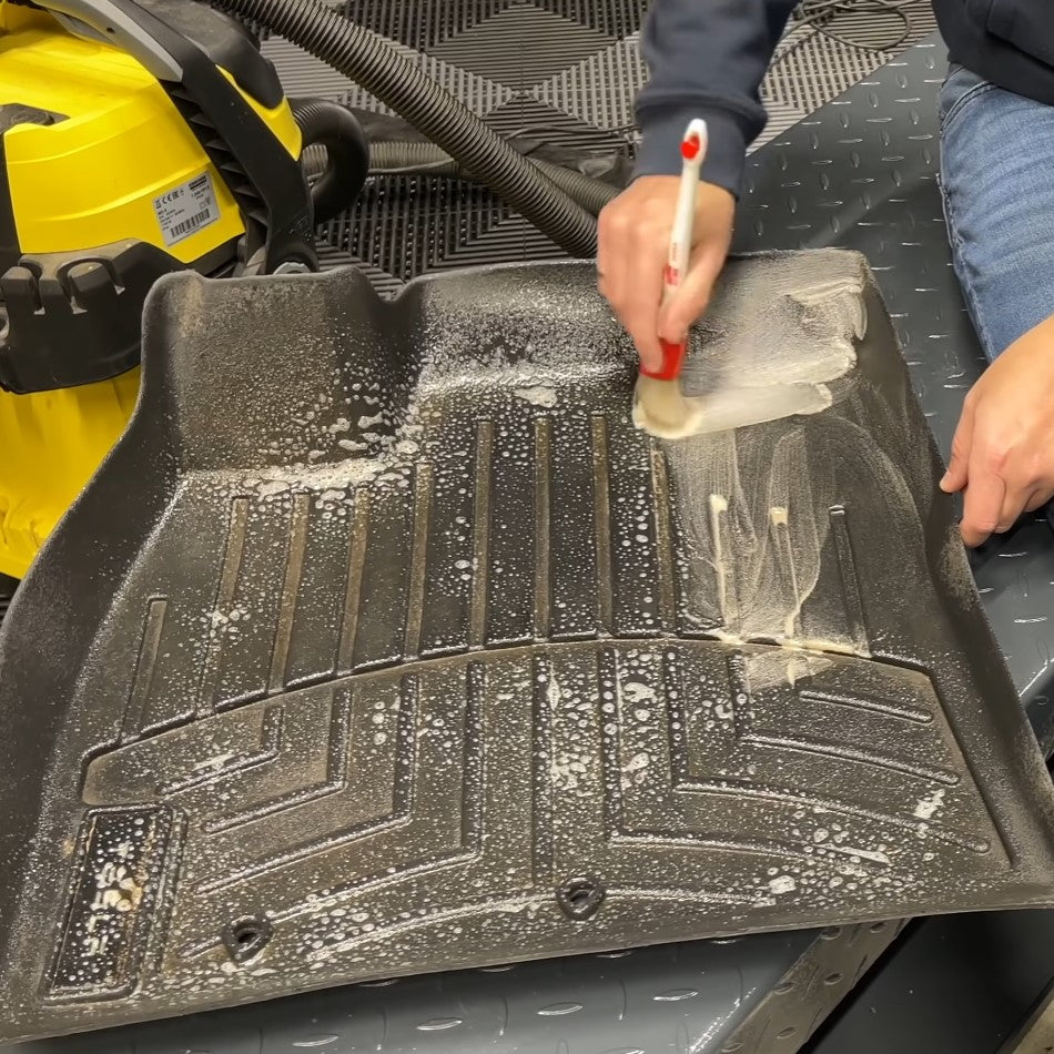 Using a detail brush to clean rubber mats