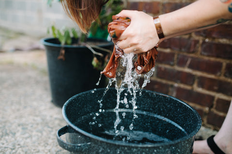 The Artist in her studio rinsing a natural dye bath from a shirt