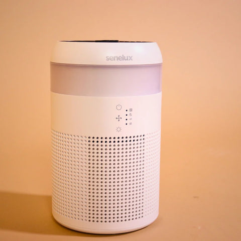 A photo of the Senelux Demi Air Purifier switched off against a warm and vibrant orange background