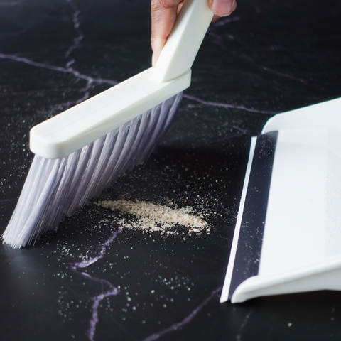 A picture of a dust pan and brush being used to clean up dust in a home instead of an easy dehumidifier